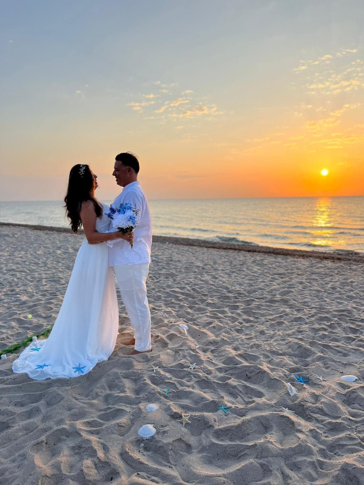 Newlyweds standing together at sunset on a beach