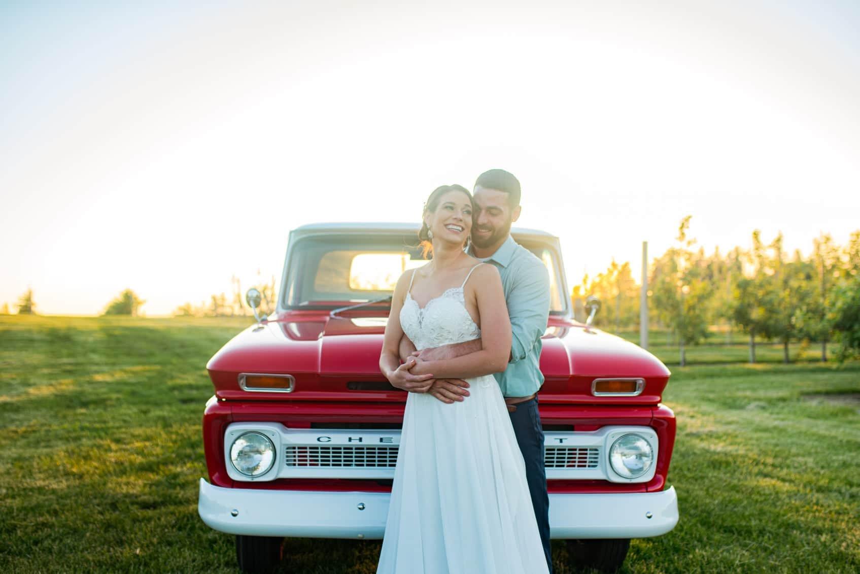 Newlyweds posing in front of a vintage red truck