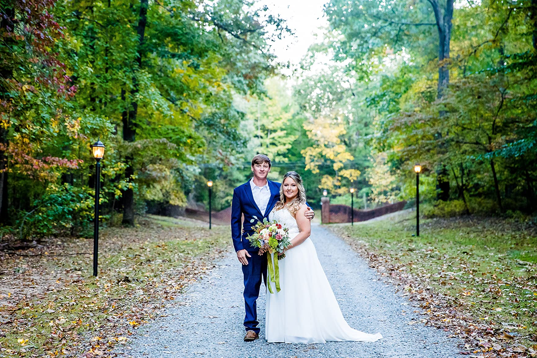 Newlyweds standing on a woodland path